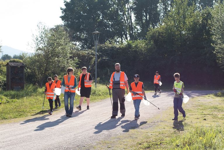 Kinder und Erwachsene in Warnwesten kehren von Müllsammelaktion zurück