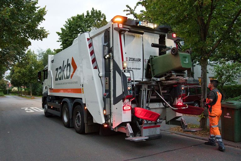 Leerung eines Abfallbehälters hinter einem Abfallsammelfahrzeug
