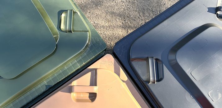 Drei verschiedenfarbige Abfallbehälter aneinander gestellt